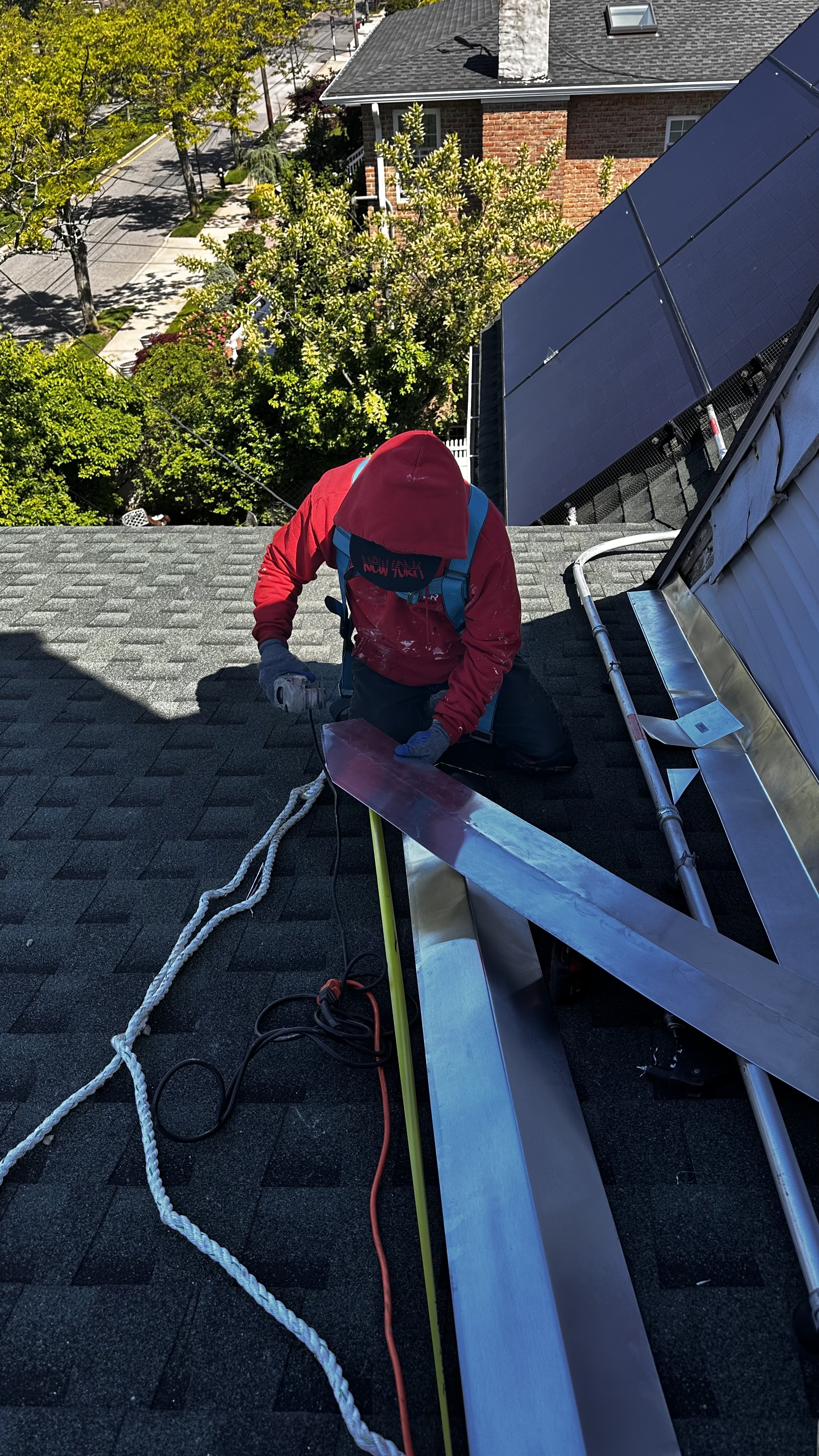 Roofer installing flashing near solar panels